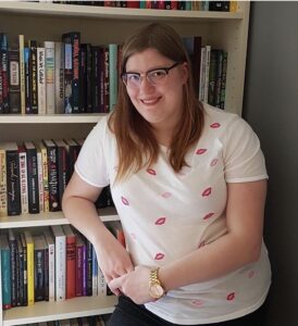 Emma Johansson står framför en bokhylle och ler. 
